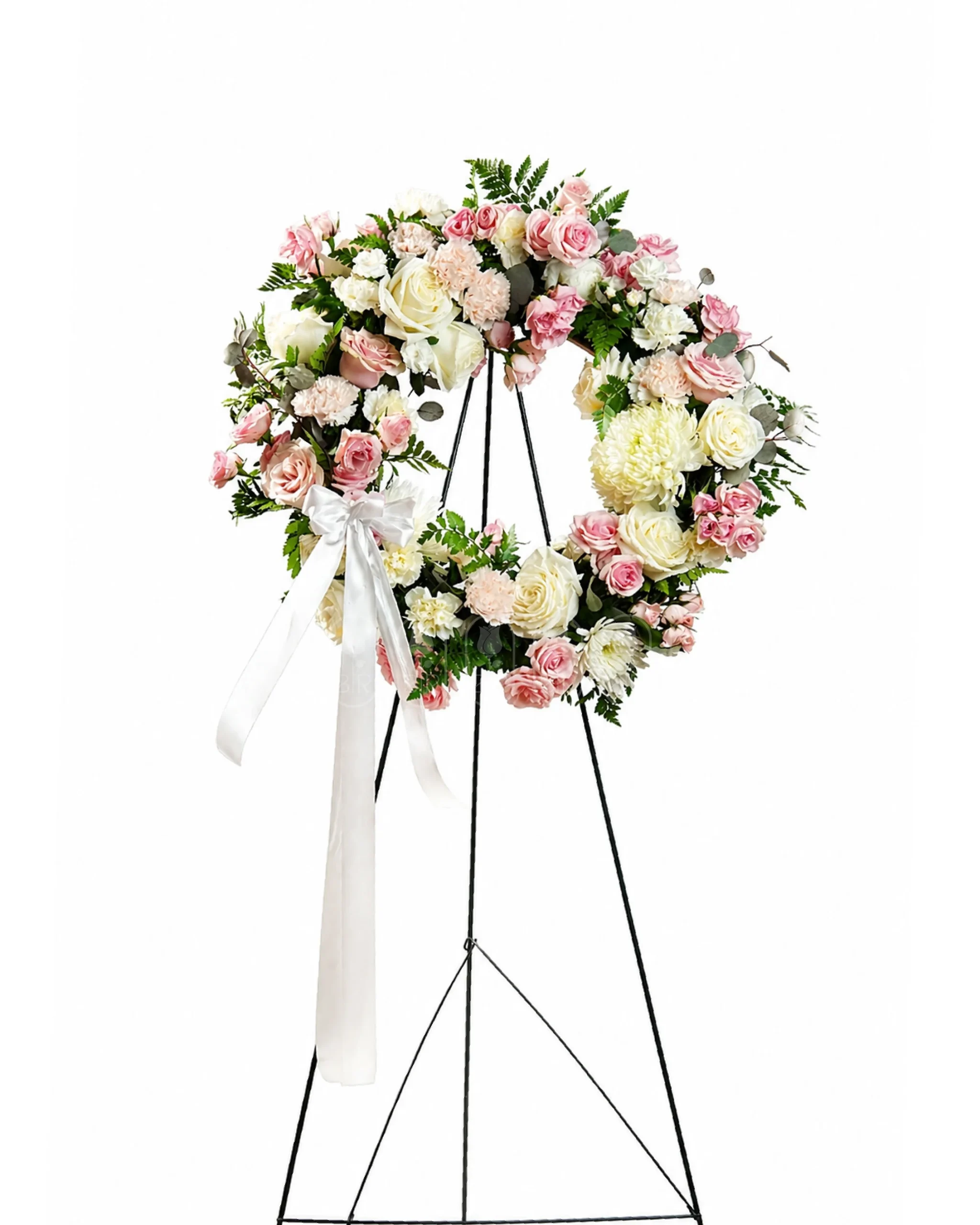 Elegant pastel funeral wreath arrangement with pink and white roses on a standing floral easel