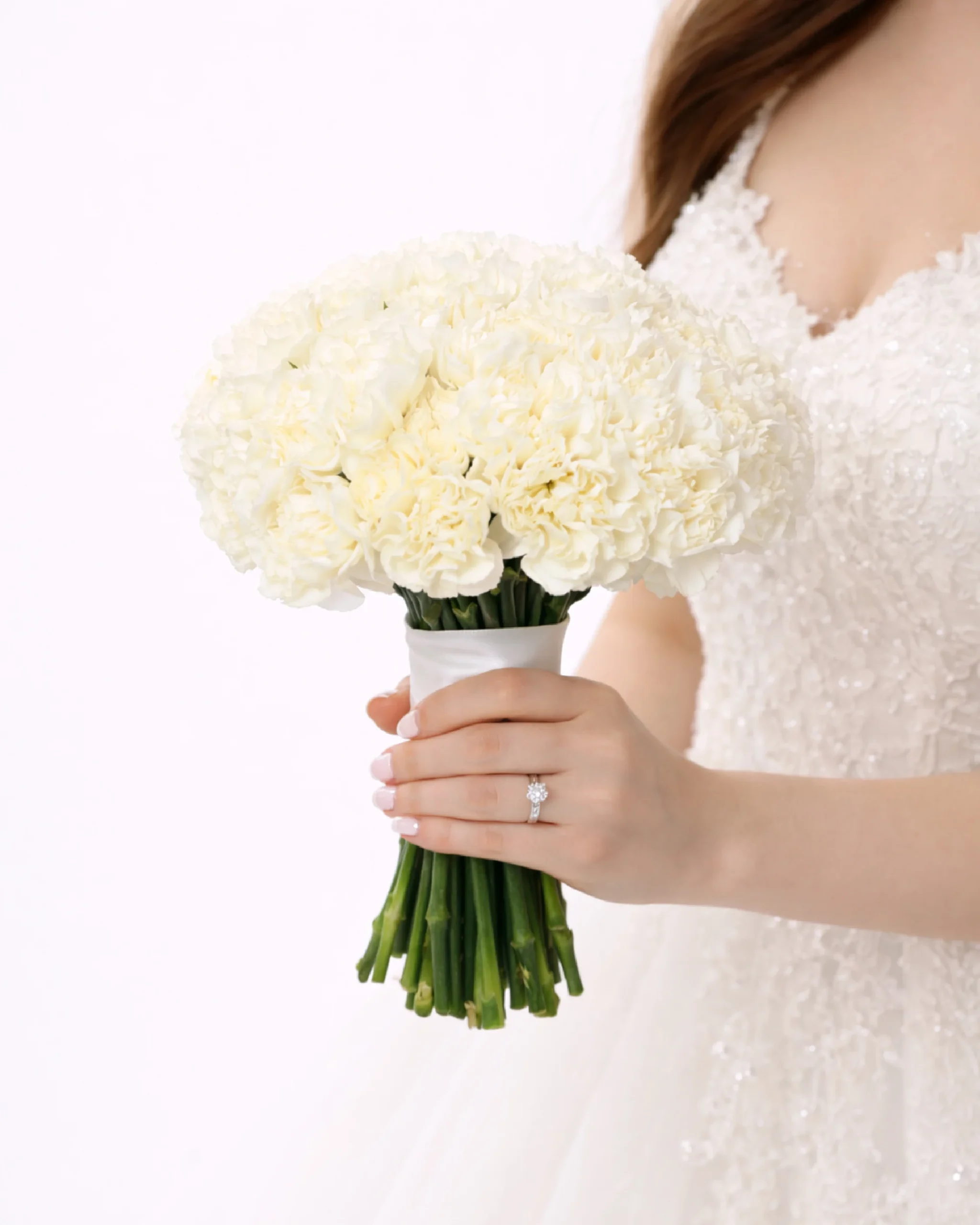 Elegant white carnation bridal bouquet held by a bride in a wedding dress