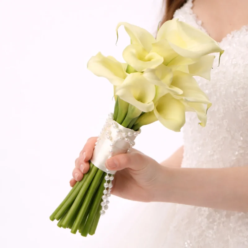 Elegant white calla lily bridal bouquet held by a bride in a wedding dress