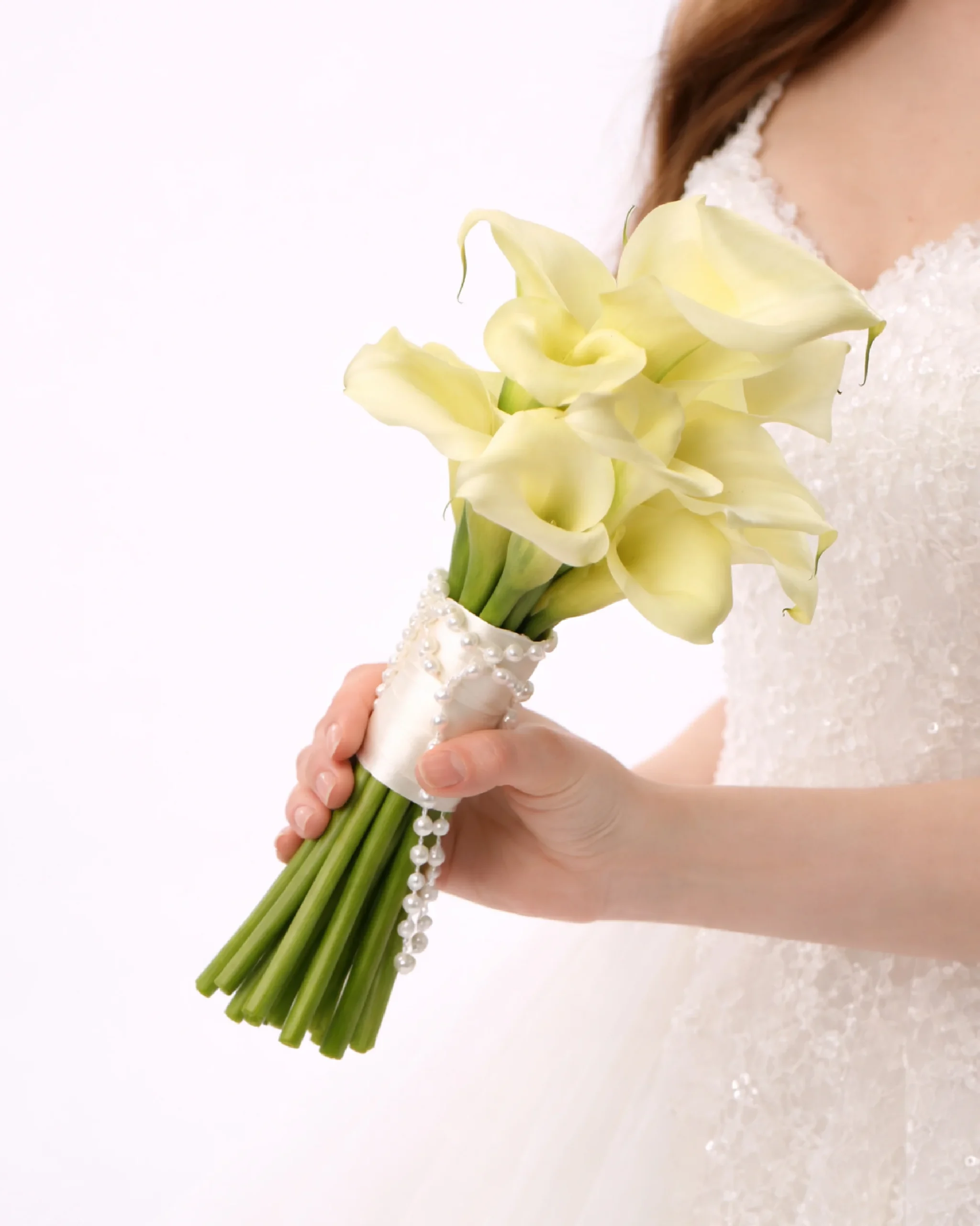 Elegant white calla lily bridal bouquet held by a bride in a wedding dress