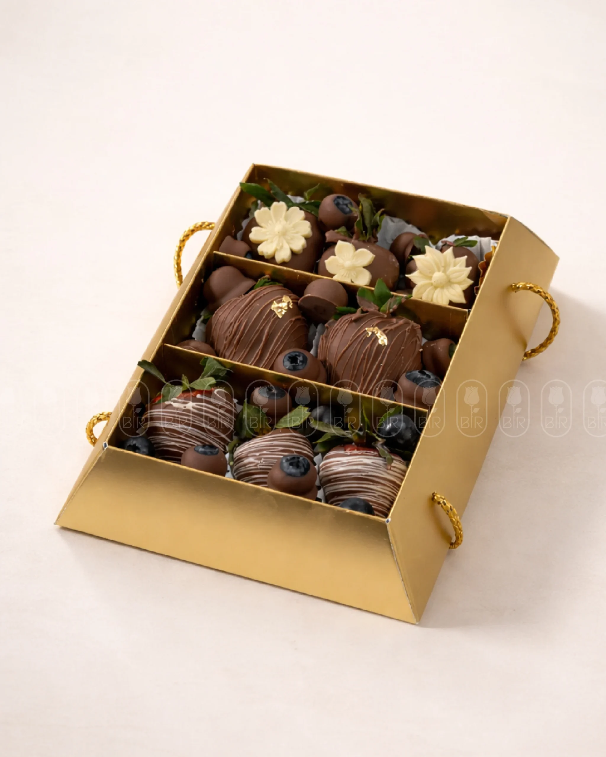 Luxury golden box filled with milk chocolate-dipped strawberries decorated with blueberries and white chocolate details