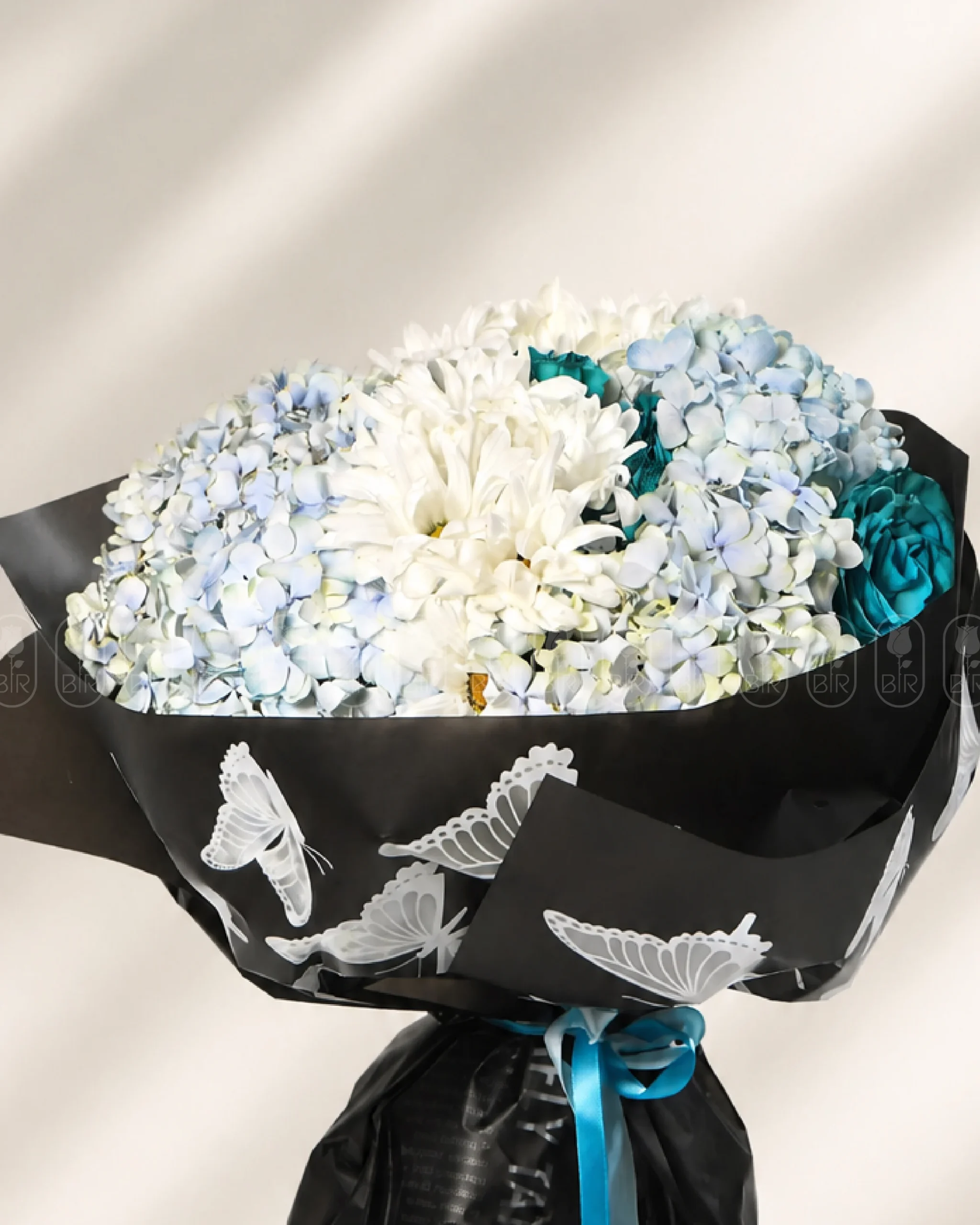 Elegant blue hydrangea bouquet with white chrysanthemums and turquoise roses wrapped in black butterfly paper