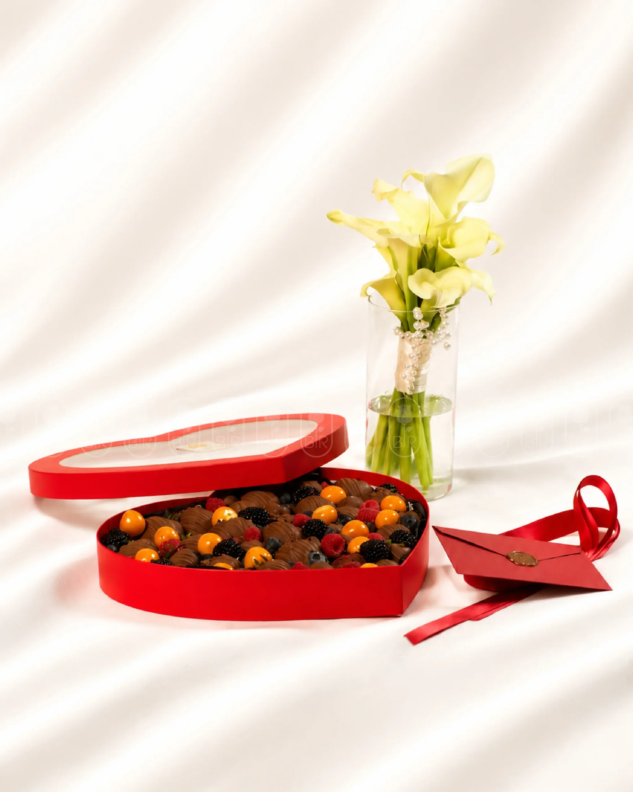 Elegant white calla lilies with heart-shaped Belgian chocolate strawberry box and berries