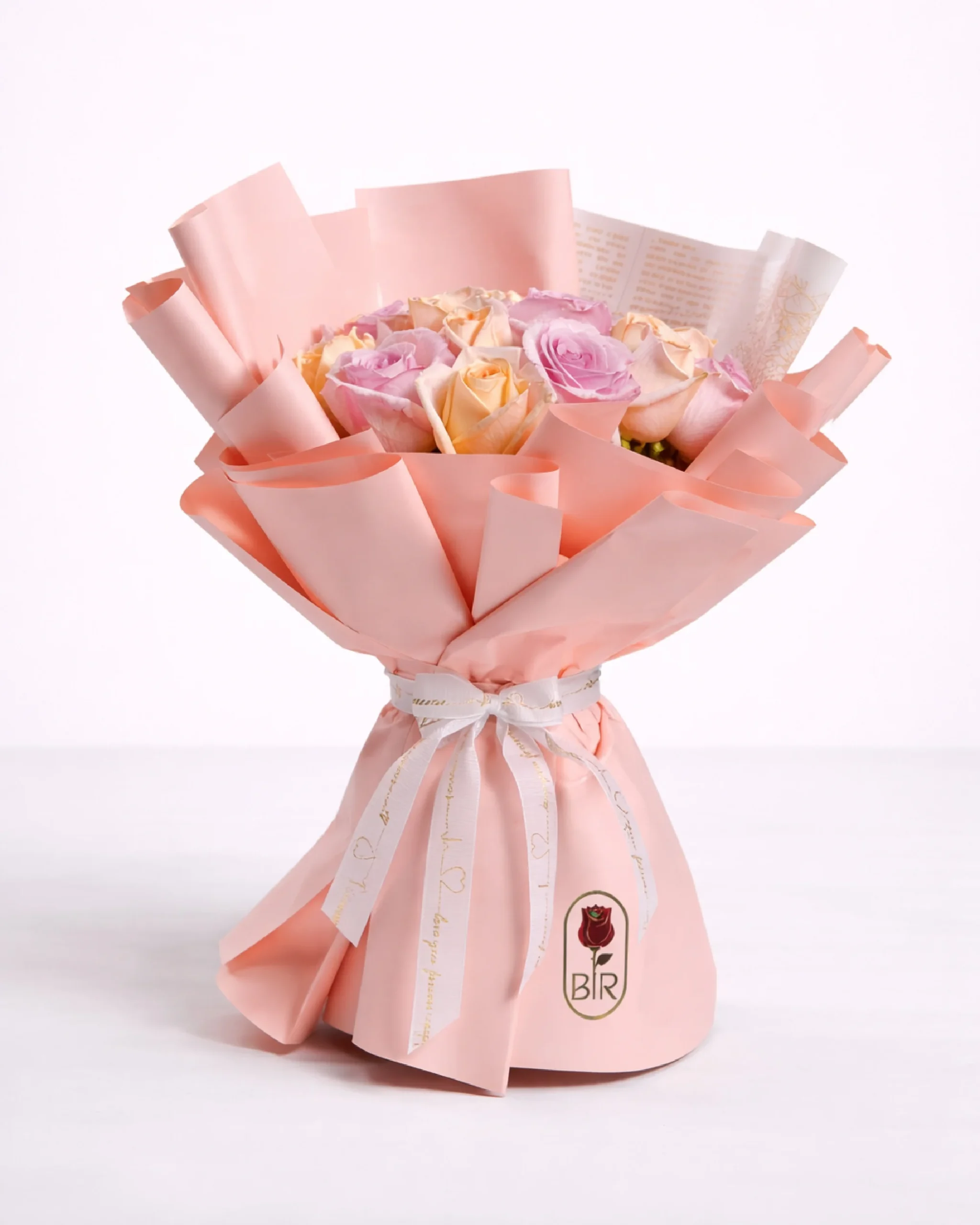 Pastel rose bouquet in peach wrapping with white ribbon