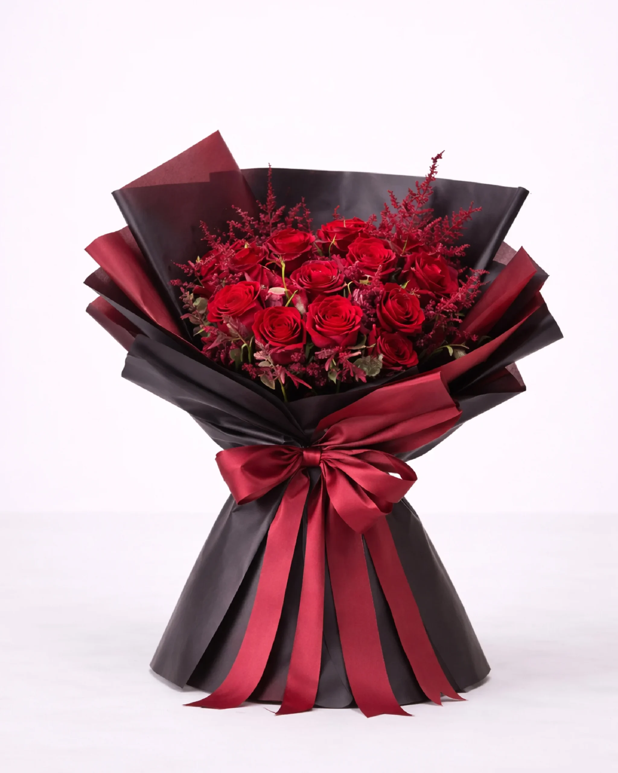 Elegant red rose bouquet with dark wrapping and matching red ribbon