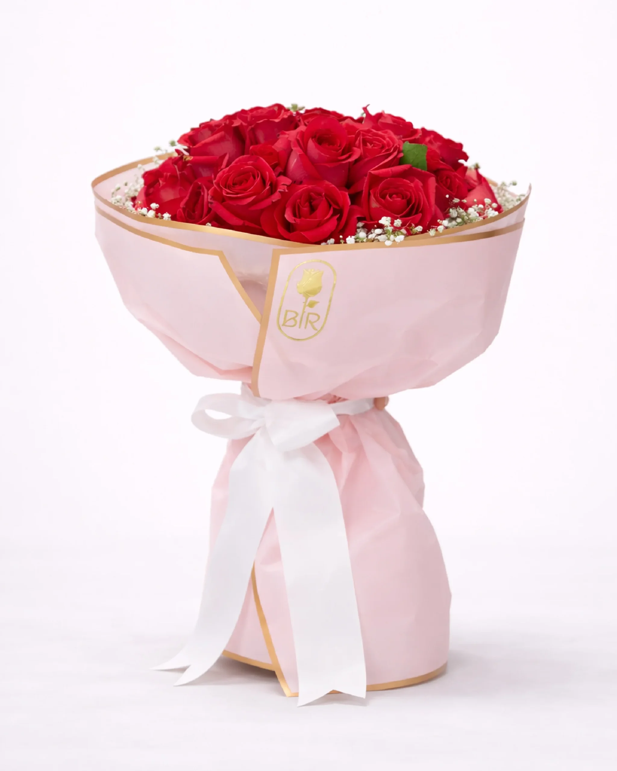Red rose bouquet wrapped in soft pink paper with white ribbon