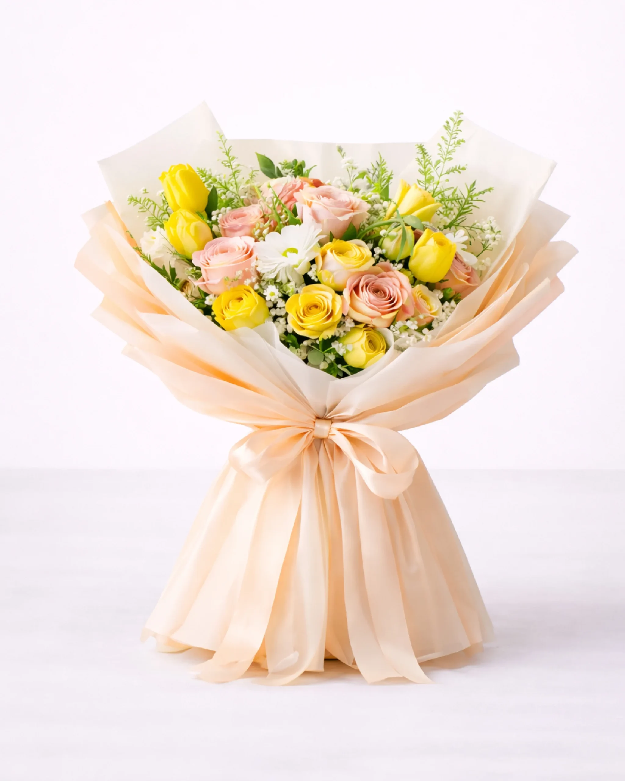 Assorted spring flower bouquet with yellow tulips and peach roses wrapped in soft beige paper