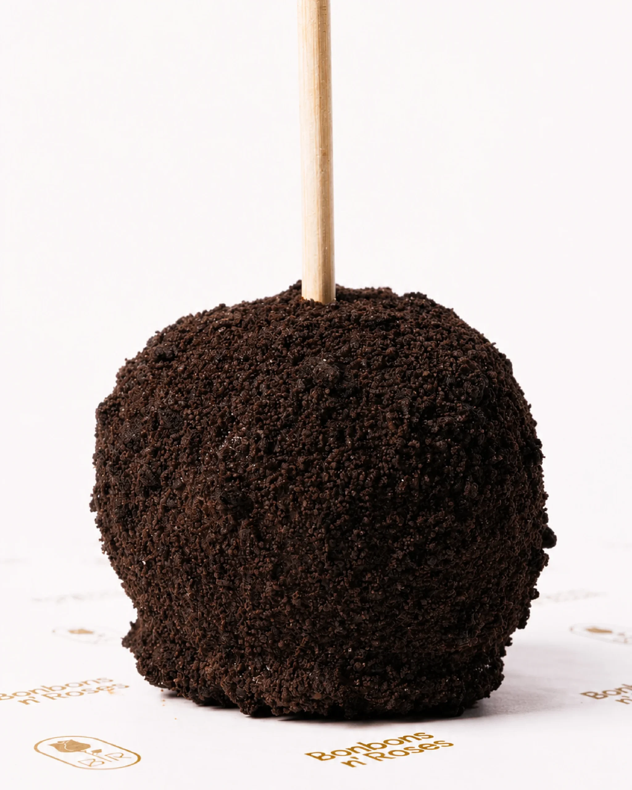 Handcrafted gourmet caramel apple coated with fine dark chocolate cookie crumbs.