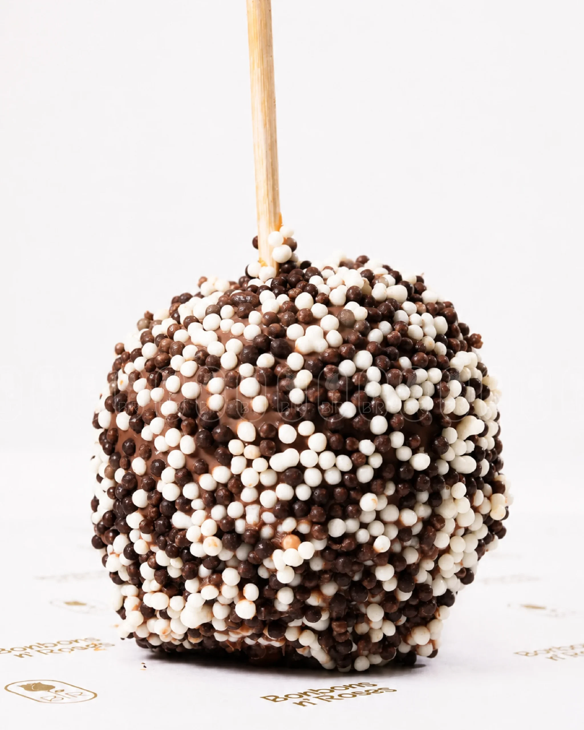 Handcrafted gourmet caramel apple coated with crispy milk and white chocolate pearls.