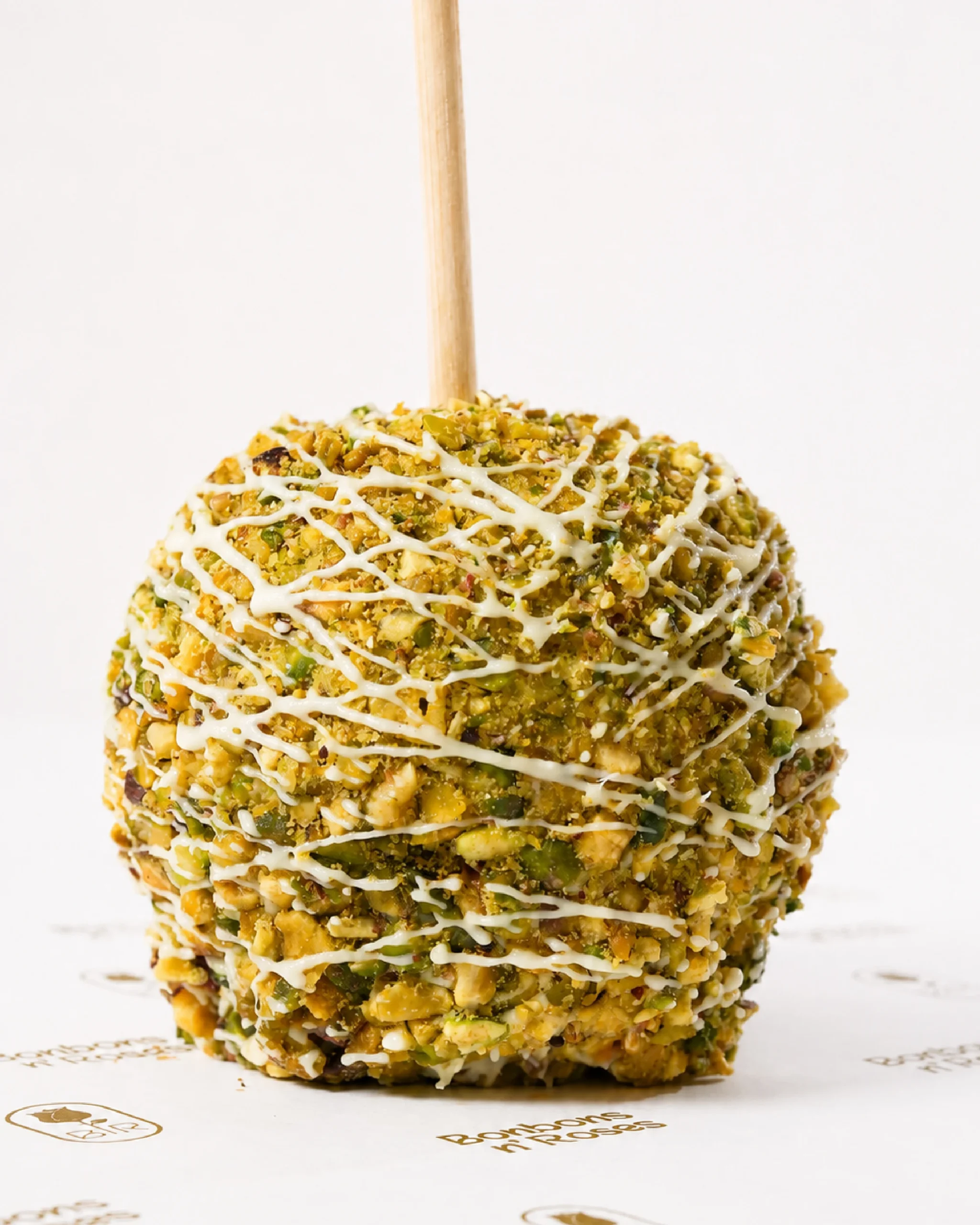 Gourmet caramel apple coated with roasted pistachios and finished with a premium white chocolate drizzle.